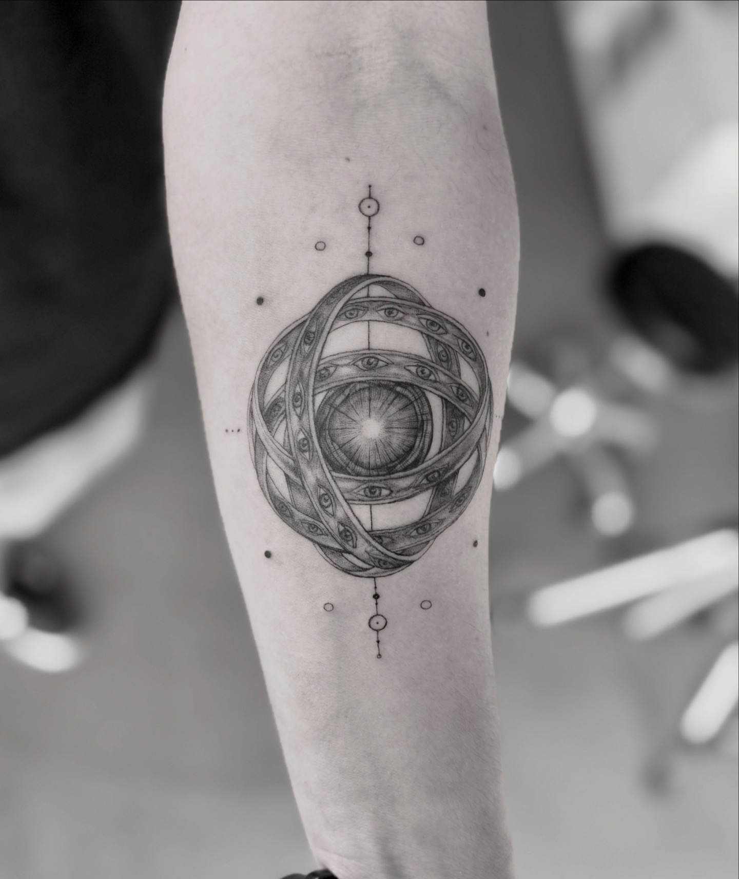 Detail of a geometric orbital eye tattoo on the forearm